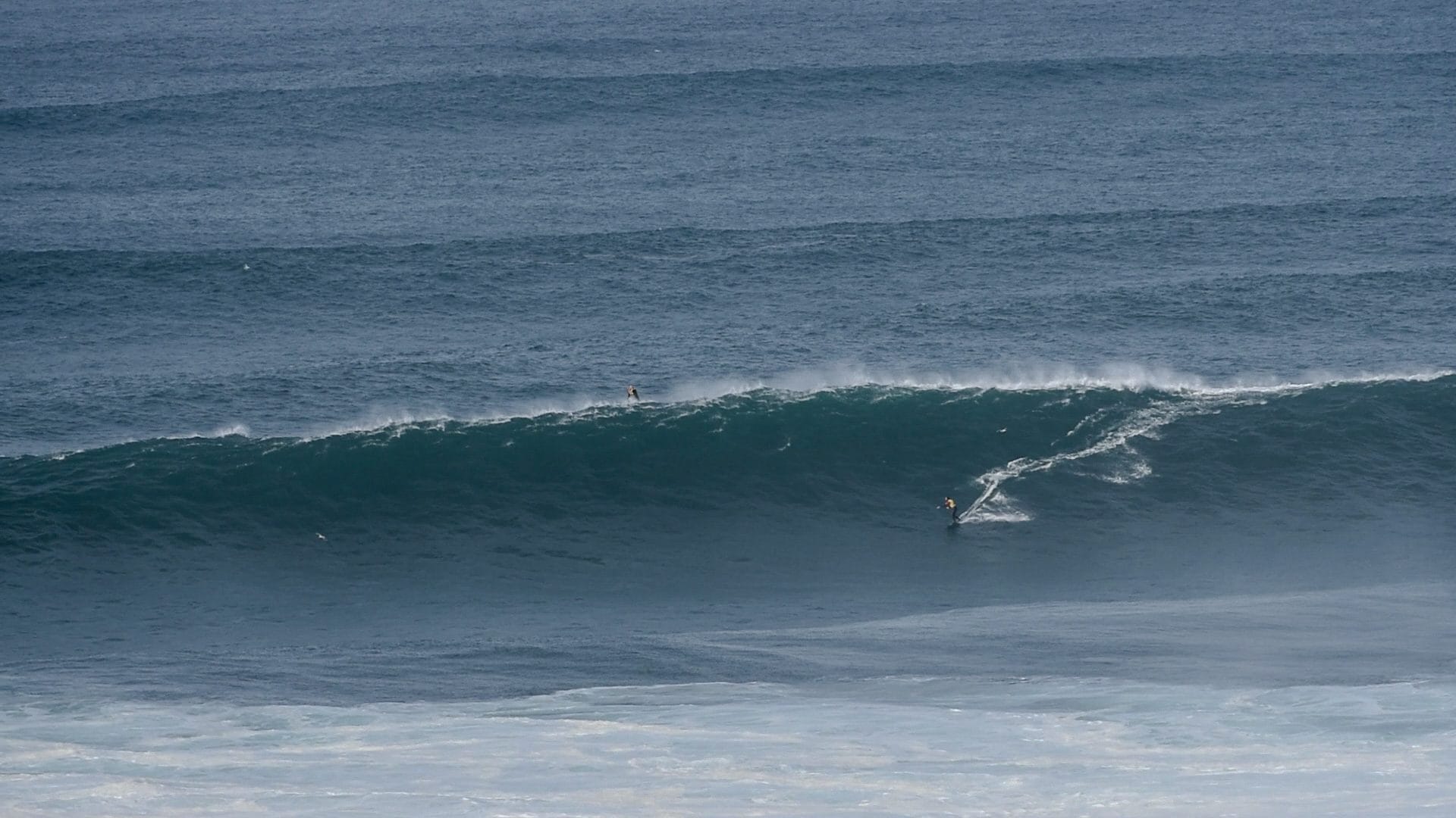 Surfer riding a big wave at Nazaré with the jet ski driver in position, the moment Galileo X-Plorer came to film